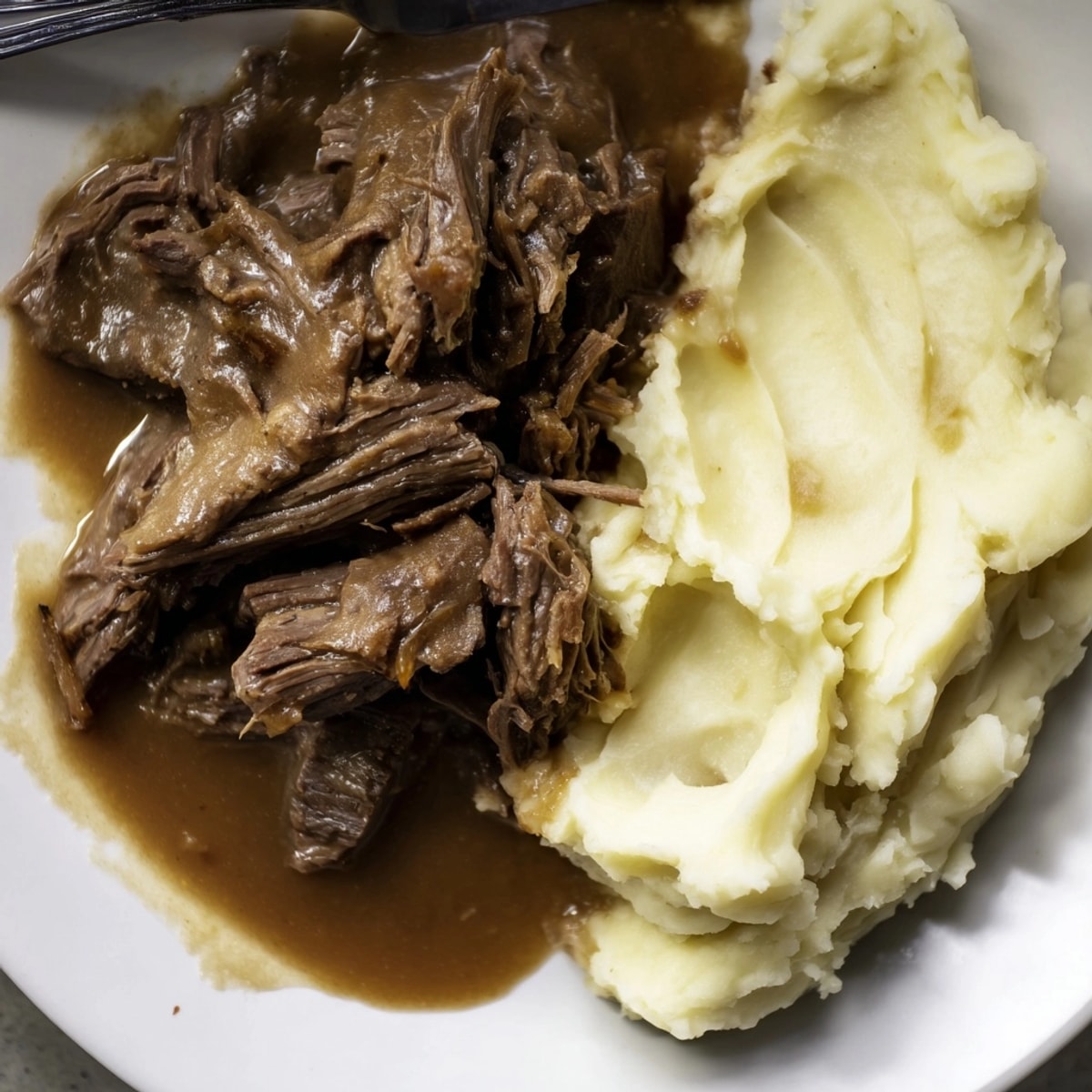 Juicy pot roast with mashed potatoes: Tender, fork-pulled beef, creamy, comforting supper.