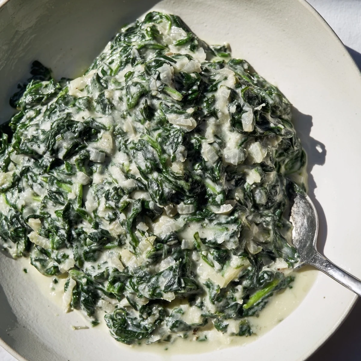 A warm skillet of creamed spinach, rich in garlic flavor and topped with Parmesan cheese.