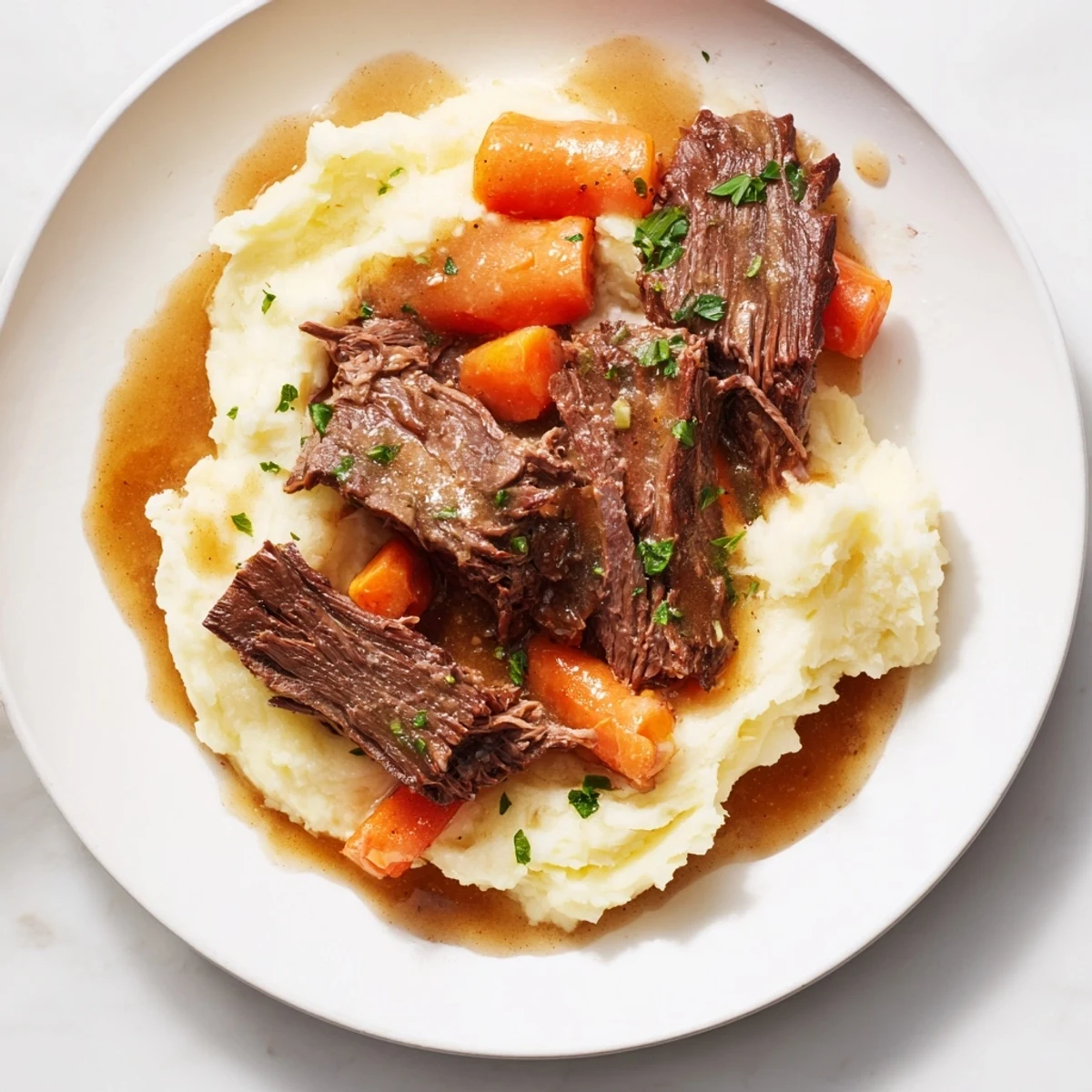 Tender Slow Cooker Pot Roast resting on a fluffy bed of creamy, homemade mashed potatoes.