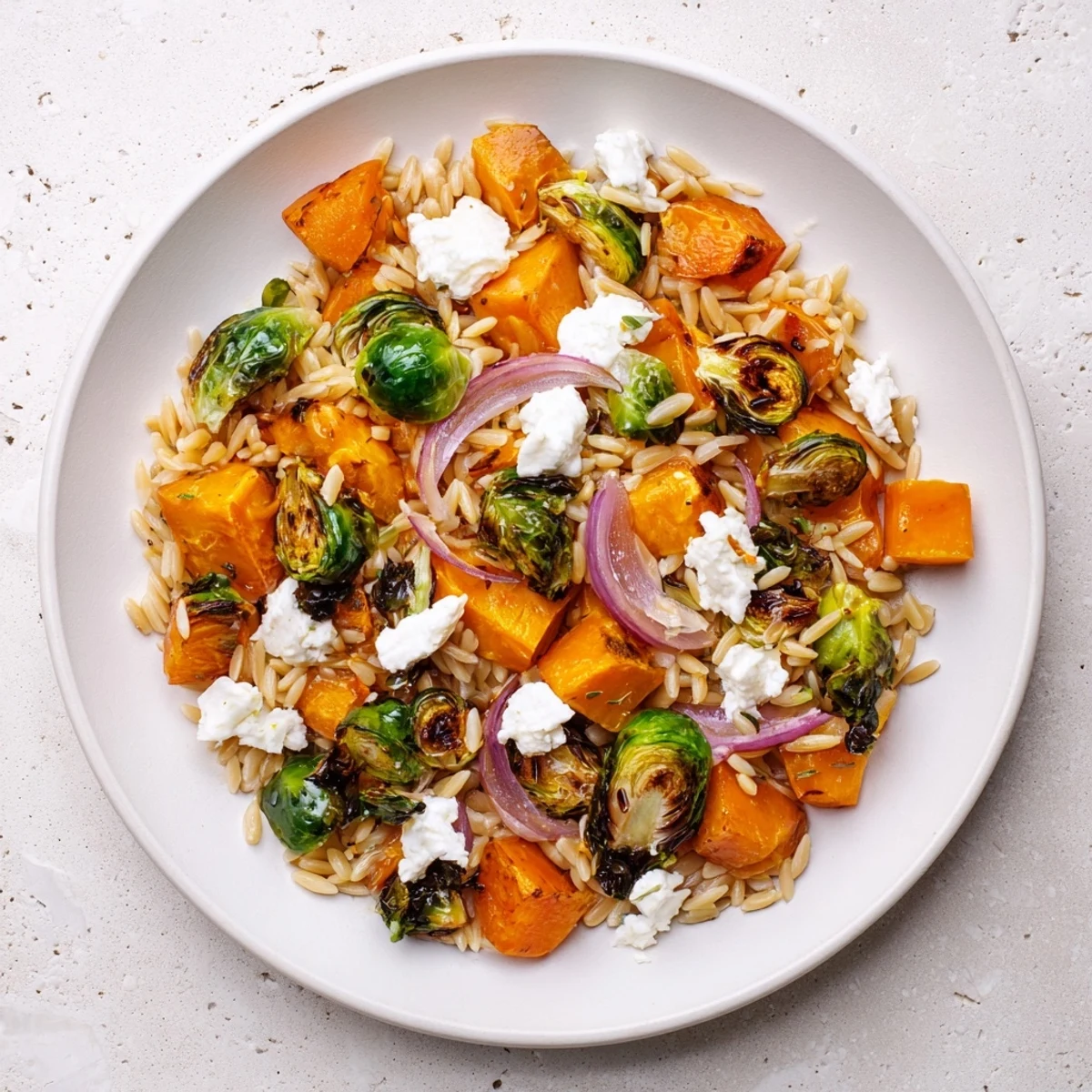 A colorful bowl of Best Fall Harvest Orzo Salad with roasted veggies and creamy goat cheese.