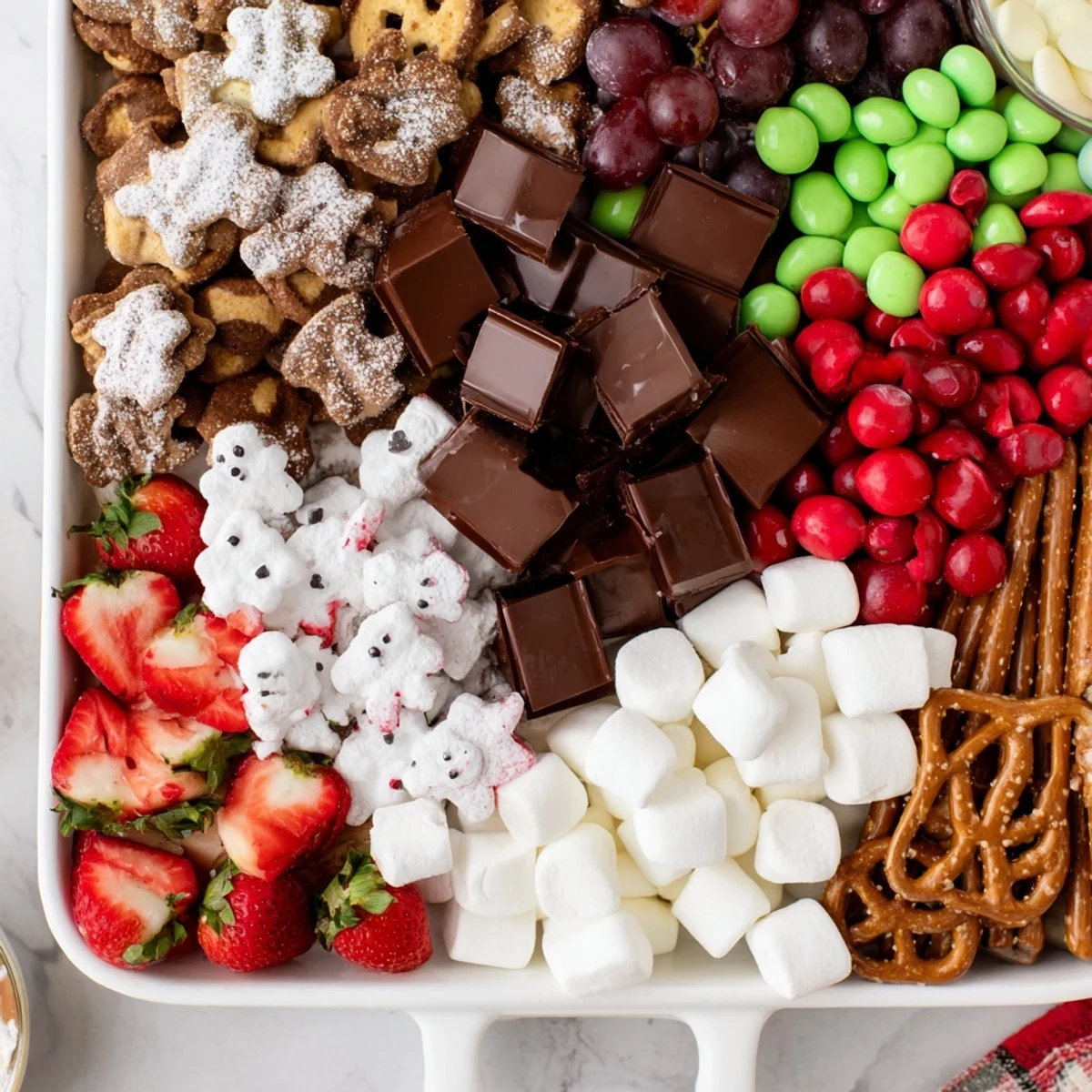 A festive Cozy Mitten Dessert Board overflowing with treats like chocolates, candies, and fruit for holiday fun.