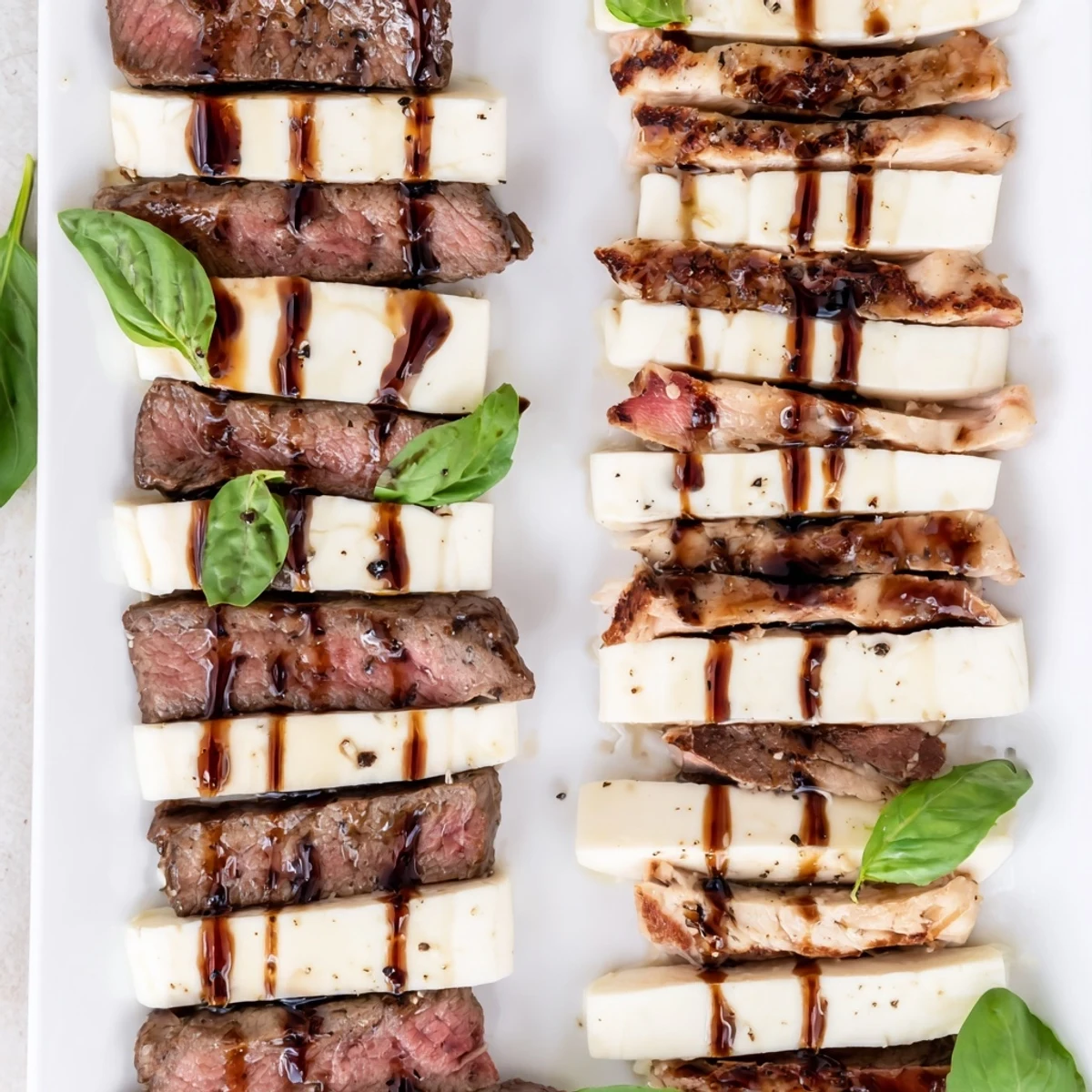Safari Stripes appetizer: alternating rows of beef, chicken, and mozzarella with balsamic glaze drizzled over.