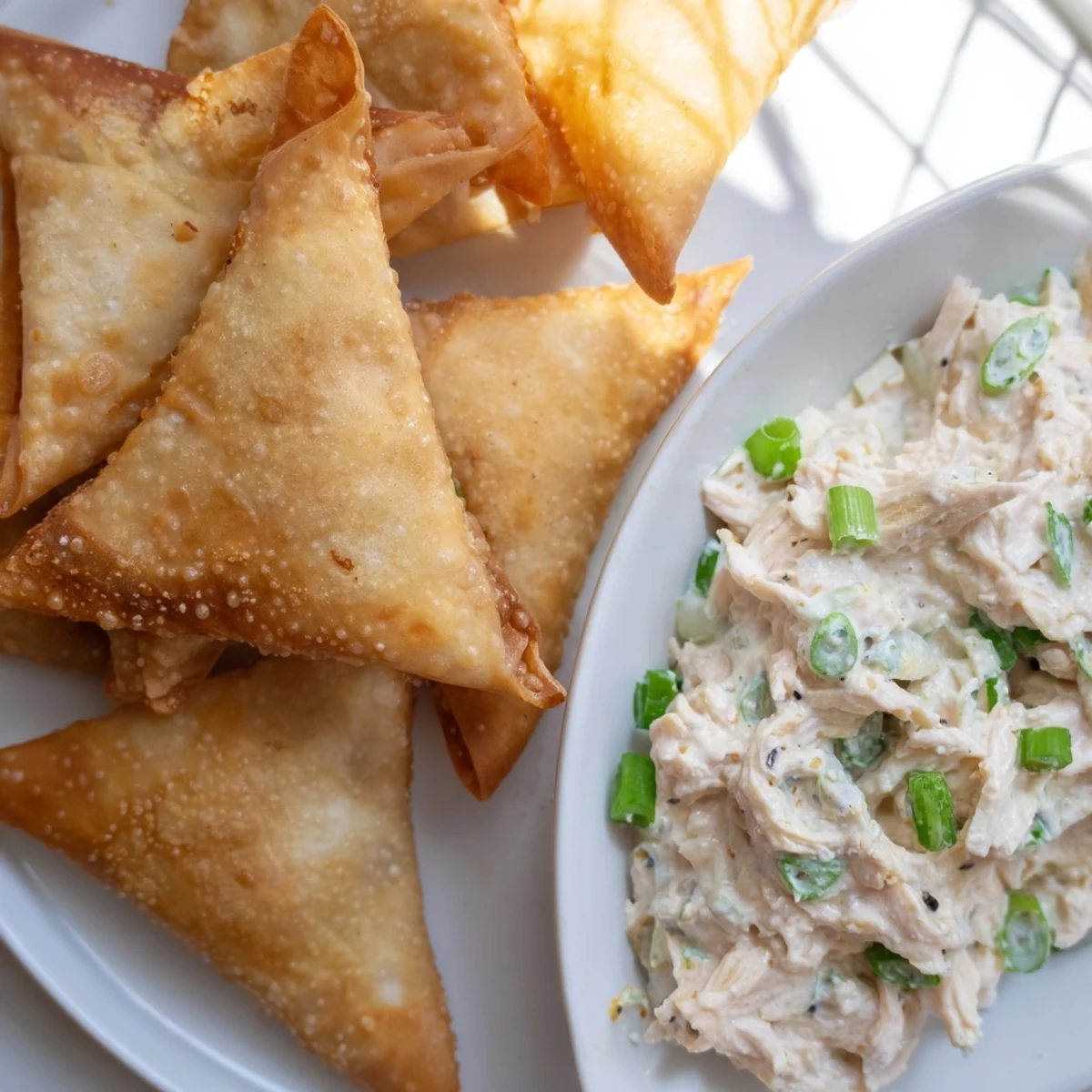 Golden, crispy air fryer lumpia chips alongside creamy chicken cream cheese dip, a delicious appetizer.
