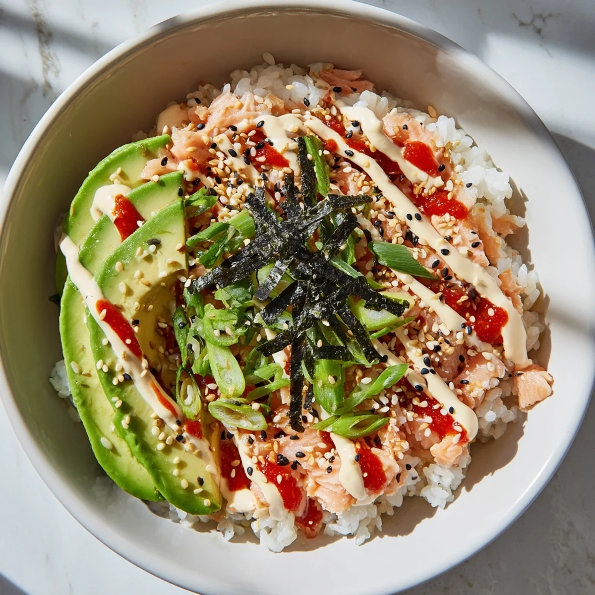 A close-up shot of Classic Salmon Rice with creamy avocado slices and toasted sesame seeds.