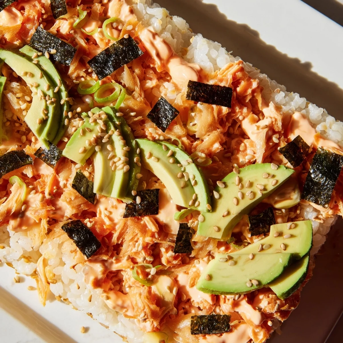 Warm, golden Sushi Bake Casserole, topped with creamy avocado and toasted sesame seeds, ready to serve.
