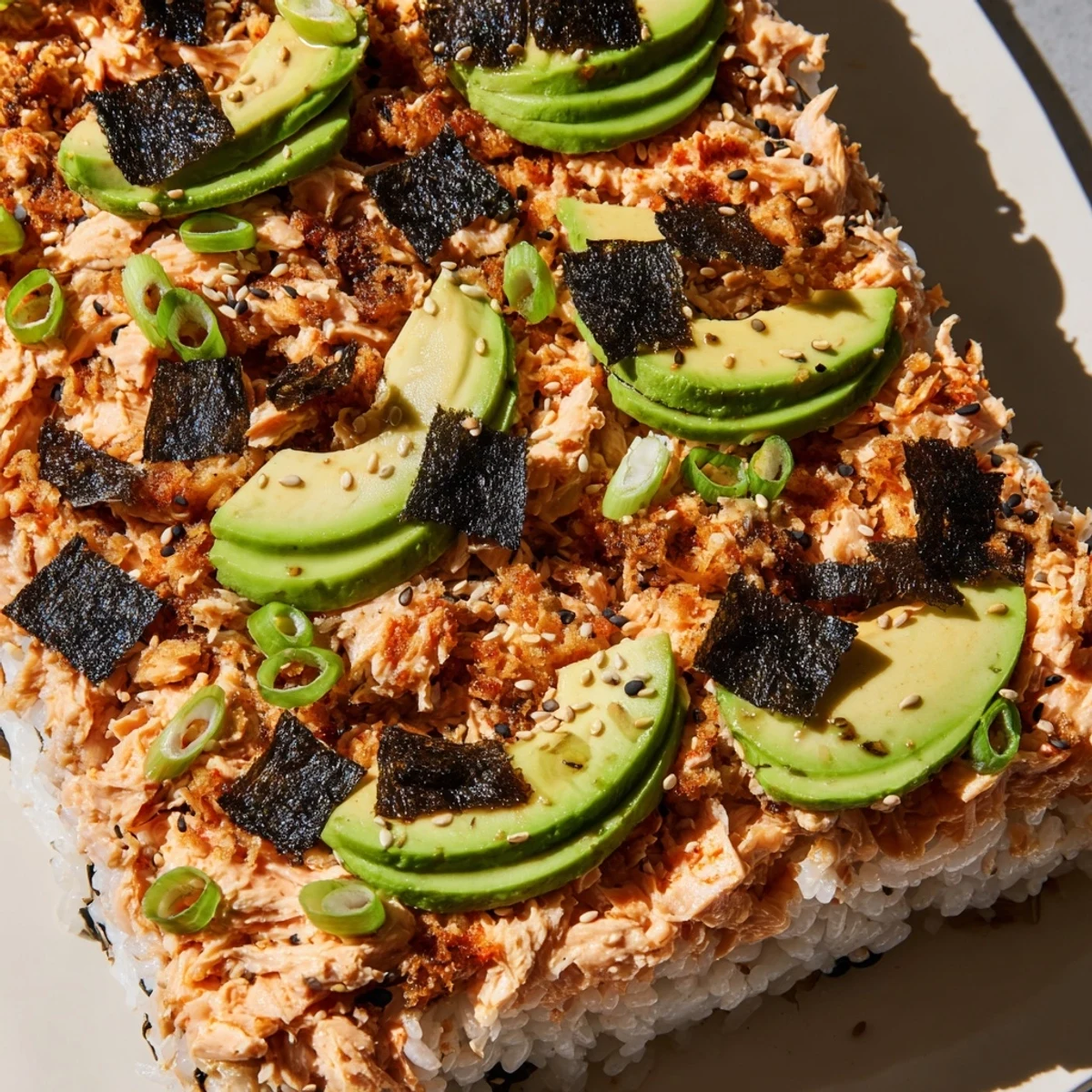 A close-up of a bubbling Sushi Bake Casserole, showing layers of seasoned rice and flaky salmon.