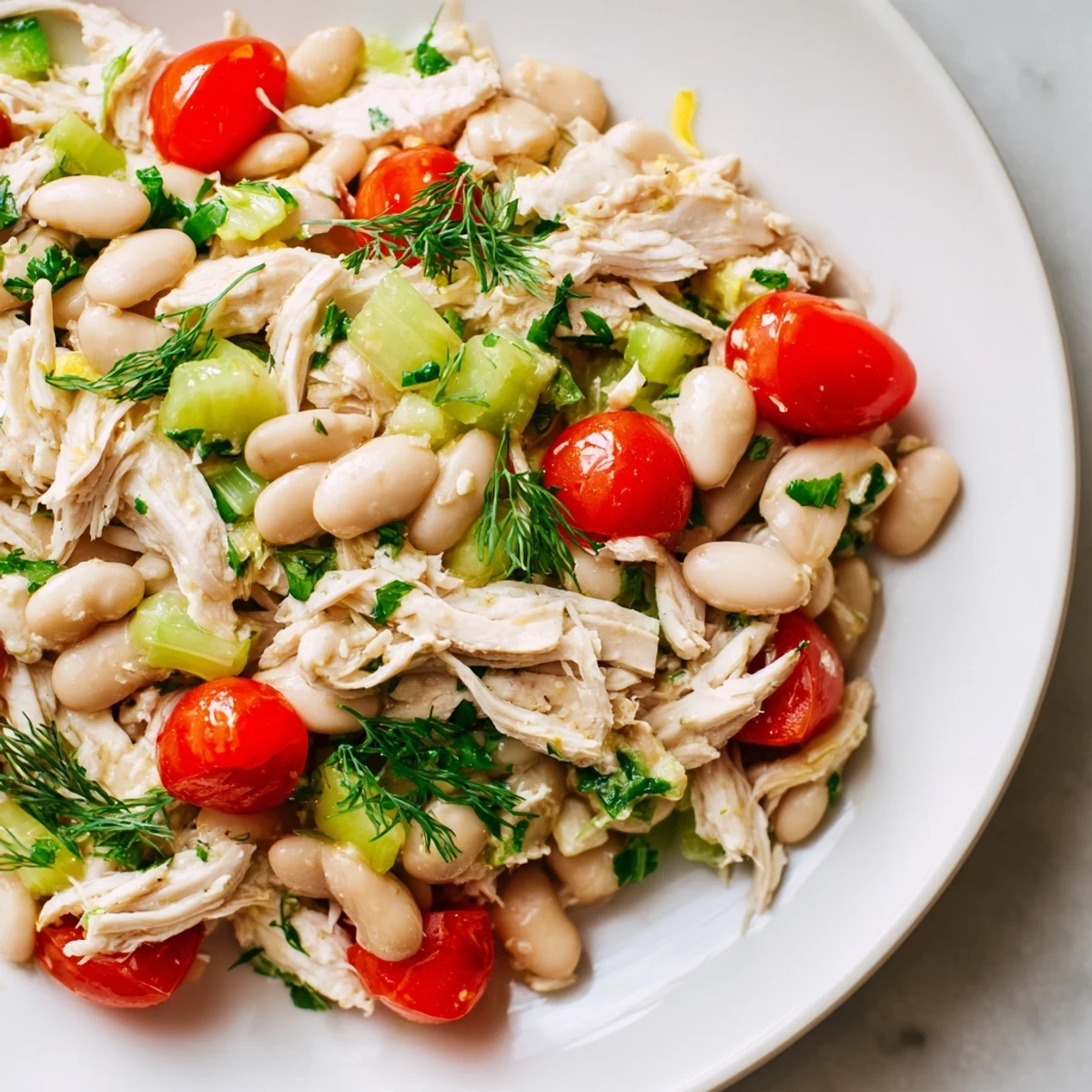 Freshly tossed Lemony White Bean Chicken Salad featuring vibrant cherry tomatoes, herbs, and a lemon vinaigrette, perfect for a light main dish.