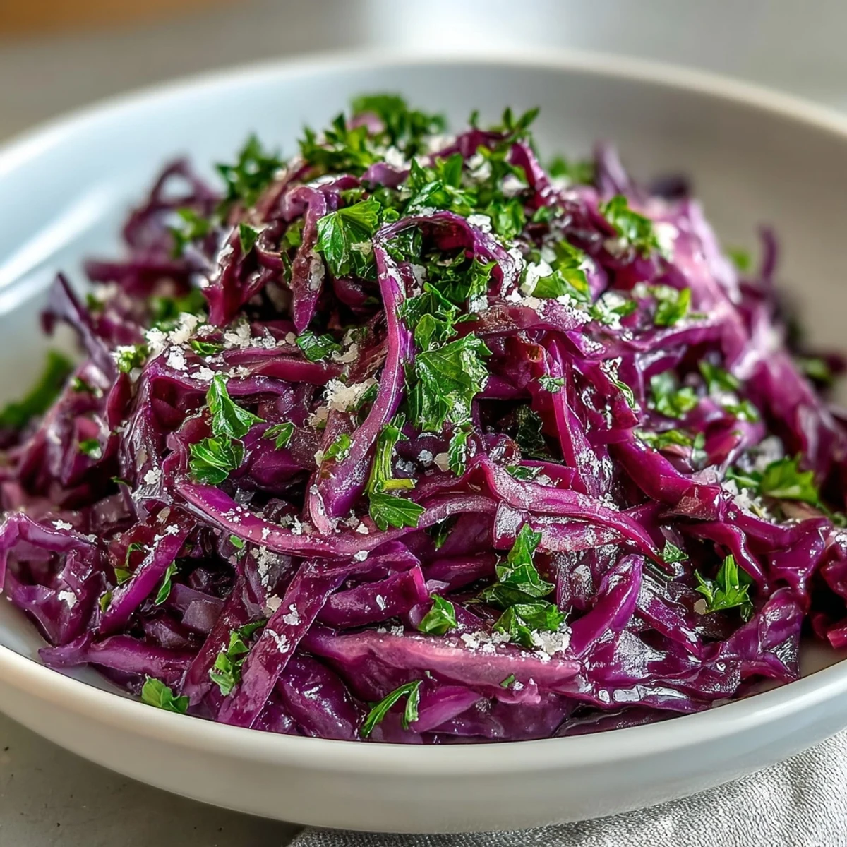 Served in a white ceramic bowl, this Red Cabbage Coleslaw With Apple and Parmesan offers a refreshing, gluten-free vegetarian meal option.