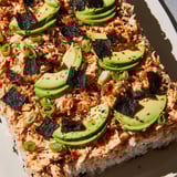 A close-up of a bubbling Sushi Bake Casserole, showing layers of seasoned rice and flaky salmon.