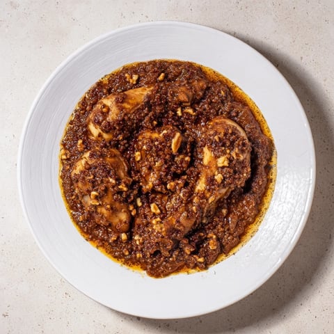 Budget Fesenjan Stew with chicken thighs glistening, served in a bowl with fluffy basmati rice.