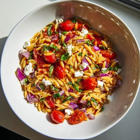 A colorful bowl of Tomato Feta Orzo, showcasing ripe tomatoes and creamy crumbled feta.