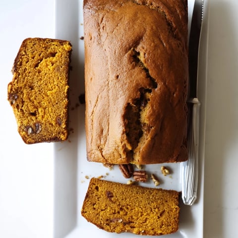 Freshly baked Pumpkin Bread Loaf, sliced to reveal a moist, tender crumb studded with chopped pecans and chocolate chips.