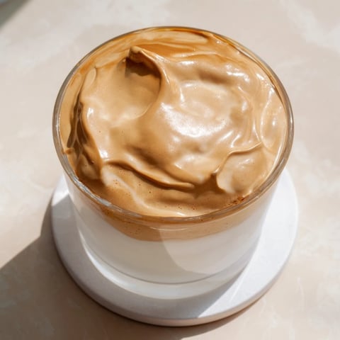A tall glass of Whipped Dalgona Coffee with creamy whipped coffee floating over cold milk and ice.  
