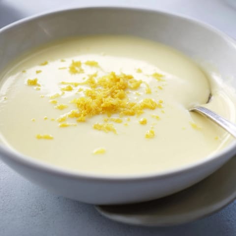Homemade Lemon Posset, a simple British dessert, garnished with lemon zest on top.