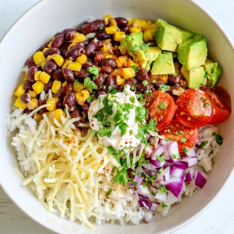 Fresh cilantro and juicy tomatoes topping this flavorful Rice, Bean, and Corn Burrito Bowl are a delight.