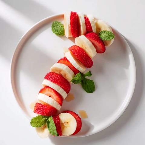 Bright red strawberries and creamy bananas form a festive Candy Cane shape—a delicious treat.