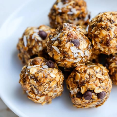 Homemade Almond-Chia Energy Bites stacked on a parchment paper lined baking sheet, ready to cool.