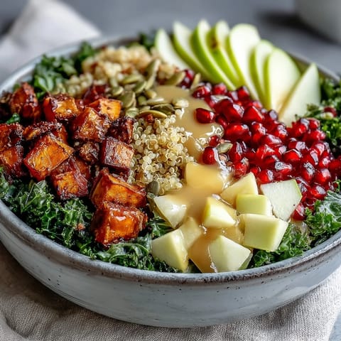 A freshly drizzled Kale Harvest Grain Bowl features fluffy quinoa, crisp apple, and golden sweet potatoes for a nourishing meal.