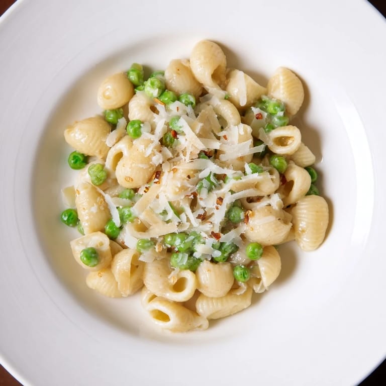 A close-up of delicious macaroni & peas, showing the creamy sauce and tender green peas.