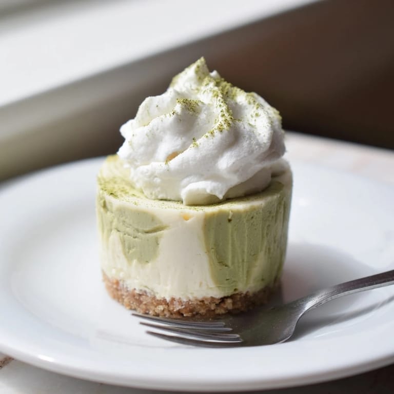 A close-up view of elegant Matcha Swirl Snowdrift Cheesecake Cups, ready to be enjoyed as a refreshing dessert.